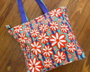 Bolso de tela impermeable con cierre. Flores rojas y rayas azules y verde agua. Mirador Art Studio