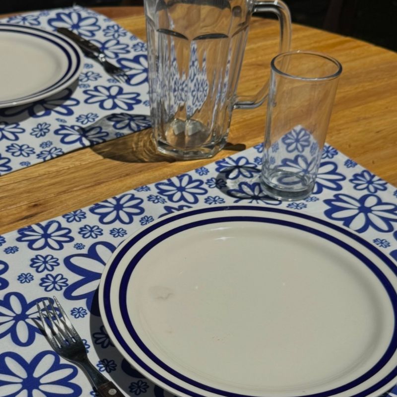 Blue and white floral pattern placemats on a wooden table, elegant home decor licensing example by Mirador Art Studio.